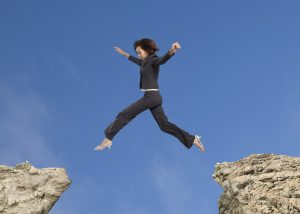 woman jumping between two rocks
